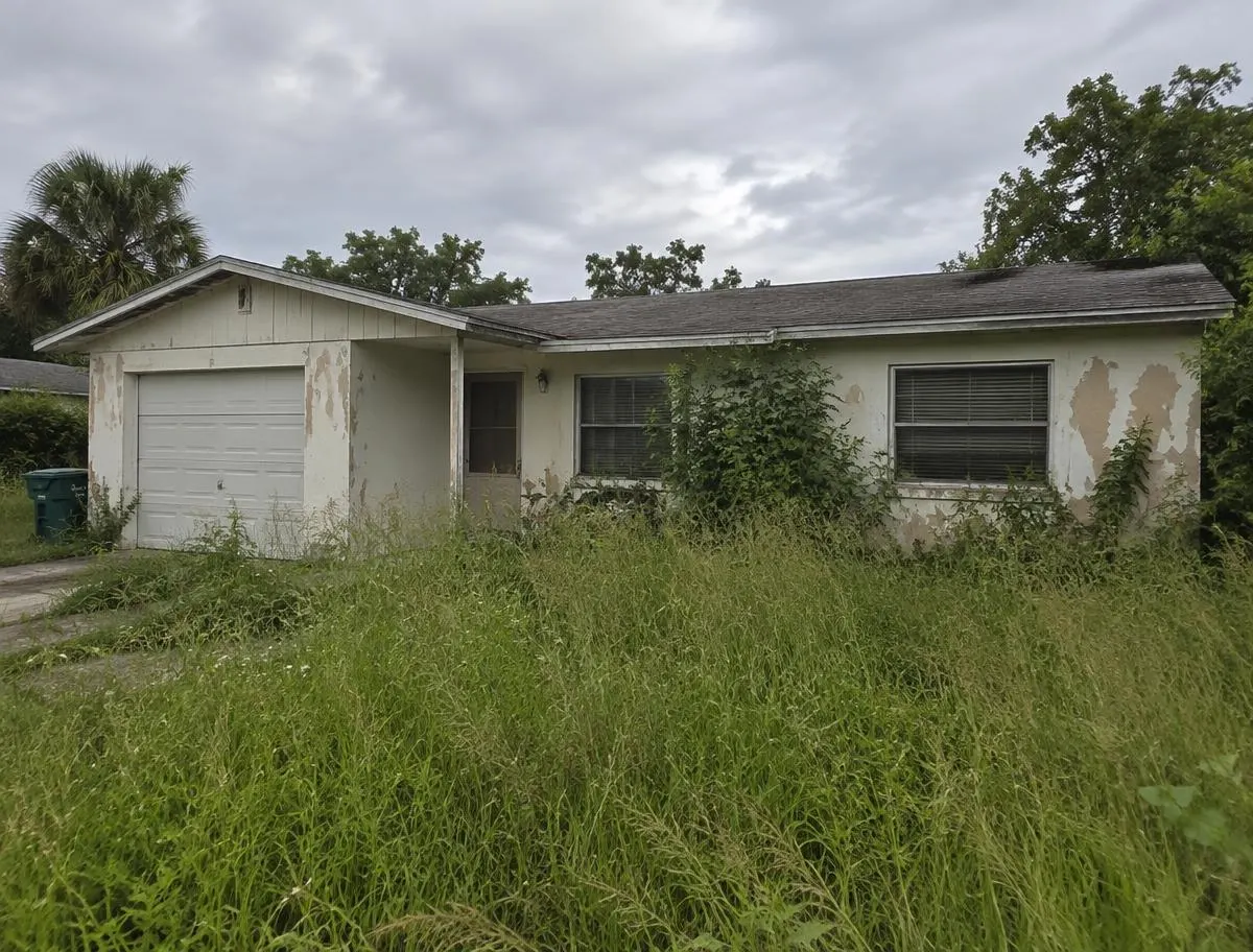 Florida house with tall grass and overgrown weeds